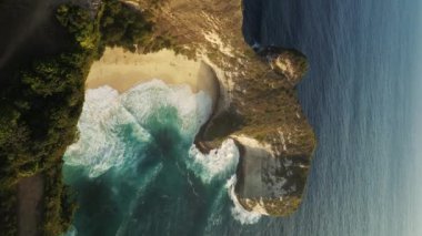 Dikey video. Kelingking Sahili 'nde Derin Okyanus Dalgaları' yla T-Rex Kayalıkları 'nın insansız hava aracı görüntüsü. Turist Ziyaret Etmeli Yeri. Bali 'deki Nusa Penida Adası' ndaki Kelingking Sahili 'nin hava görüntüsü.