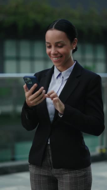 垂直录像 这位快乐的女商人站在现代写字楼外 用智能手机刻画她的形象 技术概念 — 图库视频影像