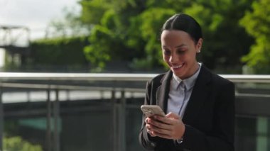 Genç iş kadını iddiayı kazanınca sevinçten havalara uçtu, telefonuna neşeyle baktı, kutlama ve başarı kavramını somutlaştırdı..