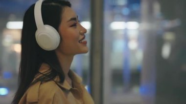 Beyaz Kulaklıklı Yakışıklı Genç Kız Yürüyor ve Müzikten Hoşlanıyor. Kulaklık takan ve alışveriş merkezinde şarkı söyleyen bir turist. Halk ve Müzik Konsepti
