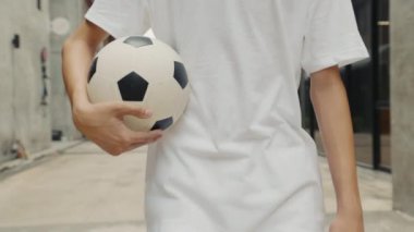 Antrenmandan sonra futbol topunu tutan çocukların yakın görüntüsü. Gençler futbol maçından sonra yürür ve futbol topunu taşır. Spor ve İnsanlar Konsepti