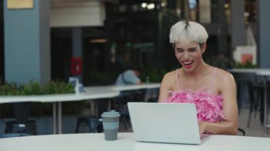 Yakışıklı, gülümseyen, pembe tişörtlü, oturan ve dizüstü bilgisayar kullanarak komik videolar izleyen ibne. Kafe 'de internette internette gezinen olumlu eşcinsel adam. LGBT ve Teknoloji Konsepti