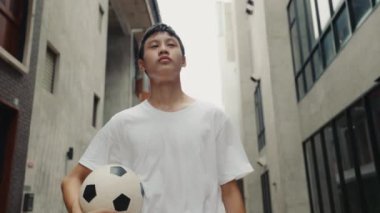 Asyalı genç futbolcu, antrenmandan sonra terleyerek evine döner ve her şeye bir göz atar. Yorgun Ciddi Adam Futbol Maçı 'ndan Eve Yürüyor ve Hayal Kuruyor. Spor ve İnsanlar Konsepti