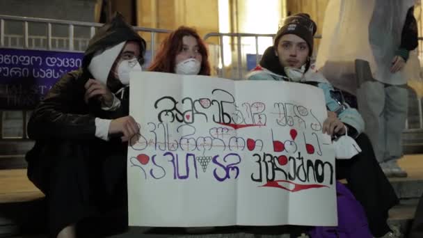 格鲁吉亚第比利斯 2024年5月12日 三名年轻的抗议者在夜间拉力赛和平地站在议会附近 举着一面标语 宣扬团结和爱 — 图库视频影像