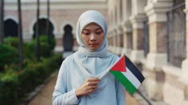 Ciddi Müslüman Kadın, Filistin Bayrağı 'yla dışarıda kameraya bakarak dikiliyor. Çekici kadının portresi Eski Bina yakınlarında vatanseverliğini gösteriyor.