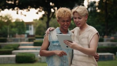 Duygusal eşcinsel çift, şehir parkında ağır çekimde yürüyen tabletle sosyal medya beslemesi yapıyor. Homoseksüel erkek partnerler internete cihaz ile giriyor. LGBTQI topluluk gurur internet etkinliği