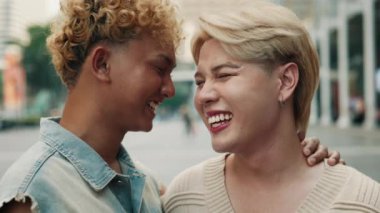 Gülümseyen Asyalı eşcinsel çift parkın manzarasında yan yana durur, birbirlerine bakar ve sıcak bir şekilde gülümserler. LGBTQ sevgisini, mutluluğunu ve birliğini kucaklamak.