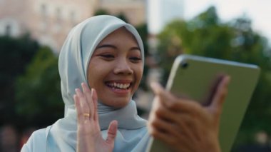 Güzel Gülümseyen Kadın Ayakta Duruyor ve Tablette Bir Konuşması Var Dışarıda Arkadaşları Karşılıyor. Çevrimiçi Konferansta Müslüman Kadın Dijital Aygıt Kullanıyor. Halk ve Teknoloji Konsepti