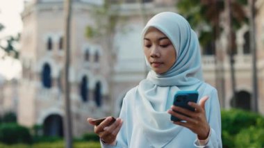 İslami Kadın dışarıda online banka ödemesi için akıllı telefonunu kullanıyor. Açık havada tesettürlü ve cep telefonundan online alışveriş yapan meşgul bir kadın. Halk ve Teknoloji Konsepti
