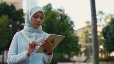 Geleneksel Giysiler Giyen Müslüman Kız Sokakta Duruyor ve Tablet 'e Bakıyor. Büyüleyici İslamcı Kadın Dijital Aygıt Üzerine Yazdırma Uygulamaları. Halk ve Teknoloji Konsepti