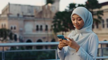 Hijab 'da genç bir kadın sokakta dikilirken Smartphone' da sohbet ediyor. Sokak Mesajlaşması 'nda Çekici Kadın, Açık Hava Telefon Kullanımı. Halk ve Telefon Konsepti