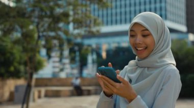 Dışarıda Başörtüsü Giyen ve Akıllı Telefon Kullanan, Ekranda Tıklayan ve Görüntülü Konuşan Genç Mutlu Kız. Çevrimiçi Çevrimiçi Konferansta Şirin İslami İş Kadını Müşterileri Selamlıyor