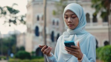 Ciddi Müslüman Kadın, sokakta dikilirken çevrimiçi satın alma ve giriş kartı detaylarını telefona aktarıyor. Güzel Müslüman Kız Fatura Ödemek için Telefon Numarasına Kart Yazıyor. Halk ve Teknoloji Konsepti