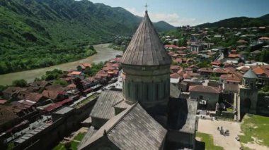 Svetitskhoveli Katedrali insansız hava aracı atışı. Mtskheta, Georgia 'da nehir kenarındaki bir kasabaya bakan antik bir kilise kulesinin havadan görünüşü, yemyeşil dağlar ve manzaralı manzaralar.