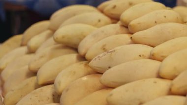 Asya yerel pazarında düzgünce istiflenmiş olgun sarı mango yığını tropikal meyve çeşitliliği sergiliyor.