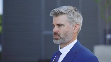 Kameraya Bakan Odaklanmış Adam Portresi. Yakın plan, kendine güvenen patron pozu. Olgun Adam Ayakta Duruyor. Ciddi Model Yüz İfadesi. Sakallı adam dışarıda kostüm giyiyor.