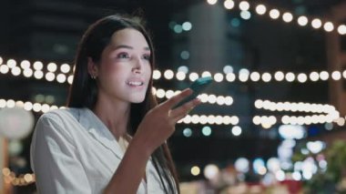 Bir gece kafesinin bayan ziyaretçisi ayakta duruyor ve telefonuna sesli mesaj kaydediyor. Güzel, Olumlu, Meşgul Restoran Sahibi Akıllı Telefon kullanarak Müşterilerle Konuşuyor. Halk ve Teknoloji