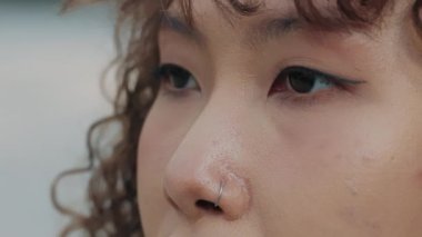 Bir kadının yakın çekimi, kahverengi gözlerini açan kadın, çekici Asyalı kadın pozu. Doğal Güzellik. Piercingli Burunlu Güzel Kız. Yavaş Hareket.