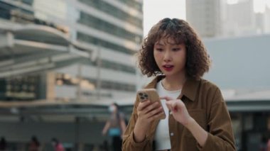 Açık havada cep telefonunun tadını çıkaran mutlu kadın. Neşeli kız telefonda iyi haberler okuyor, şaşırmış hissediyor. Halk ve Teknoloji Konsepti