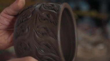 Koyu kahverengi çömlek eşyasına dönüşmek ve doğal süsleme ile dekorasyonu tamamlamak. Simetrik ağaç yapraklarını iğneyle kesen yetenekli biri..