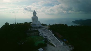 Phuket 'in büyük Buda heykeli bulutlu gökyüzü manzarasına karşı büyük dağın tepesinde. Güneş doğarken Asya tanrı anıtı turistler ve ibadet edenler için açılır. Ünlü simge.
