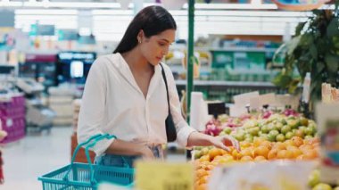 Süpermarkette meyve standının yanında duran, portakal seçen güzel bir kadın. Genç Alışverişçi Alışveriş Merkezinde Sağlıklı Ürünler Seçiyor. Alışveriş Konsepti