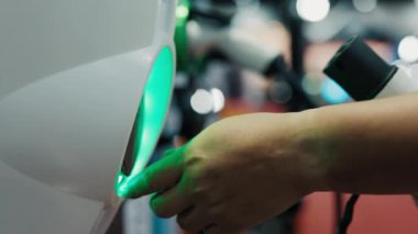 Elektrikli arabanın şarj aletinin fişini takan insanların ellerini kapat. Aracı şarj eden kadın. Halk ve Araba Konsepti