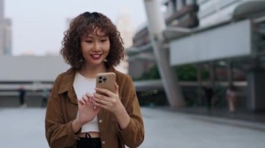 Kıvırcık saçlı kız sokakta yürüyor ve arkadaş arıyor, sohbet ediyor. Genç Asyalı bir kadın akıllı telefondan sohbet ederken ve internette gezinirken dışarı bakıyor. Halk ve Teknoloji Konsepti