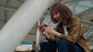 Dışarıda oturmuş elinde telefonla futbol seyreden ve takım için tezahürat yapan bir kadın. Genç bir hayran takımı kutluyor ve haykırış golü atıyor. Halk ve Futbol Konsepti