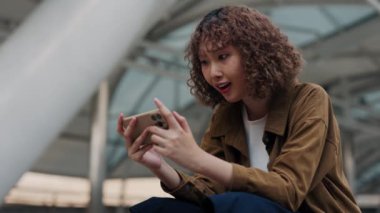 Dışarıda merdiven boşluğunda oturan genç ve güzel bir kız bahsi kazanıyor. Hevesli Kadın, Akıllı Telefonuyla İnternetten İyi Haberler Aldı. Halk ve Teknoloji Konsepti