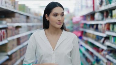 Marketin İçinde Mavi Sepetli Bir Kadın Ürünlere Bakıyor, Ürünlere Bakıyor. Genç Kız Alışveriş Merkezi 'ndeki rafları inceliyor. Alışveriş Konsepti.