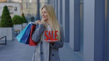 Kırmızı Satış tabelasını tutan kadının portresi, içinde çok renkli paketler var. Alış veriş sonrası uygun fiyatlı ürünlerin tanıtımı. Reklam Kavramı. İndirim günü