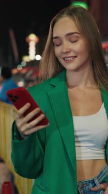 Gece şehrinde elinde akıllı telefon tutan rüya gören bir kadının portresi. Çekici genç bayan, şehir merkezinde internette sohbet mesajları yolluyor. Akıllı telefonlu bir kadın. Dikey video