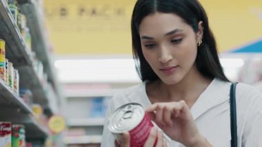 Çekici Müşteri, Alışveriş Merkezi 'nde Dururken Konserve Ürünlerin Malzemelerini Denetliyor. Sağlık Bilinci Alışverişçisi marketteki Beslenme Etiketlerini Değerlendiriyor. Alışveriş Konsepti