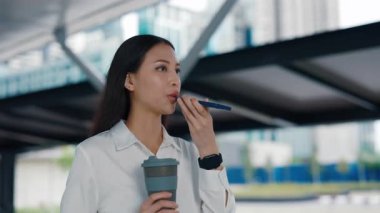Ofiste Yürüyen Asyalı Meşgul Kadın Smartphone 'una bir sesli mesaj kaydediyor. Genç ve çekici bir kız koridorda telefonuna ses komutanlığı yapıyor. Halk ve Teknoloji Konsepti