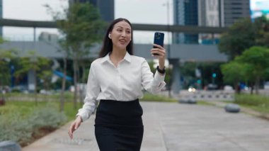 Yakışıklı genç kadın işten eve gidiyor ve arkadaşlarını arıyor. Yürüyüş ve Çevrimiçi Akıllı Telefon Konferansı 'nda Şirin İş Kızı. Halk ve Teknoloji