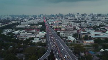 Bangkok 'un yoğun kentsel alanından geçen yoğun bir otoyolun hava görüntüsü, iki yönde de araçlar hareket ediyor. Şehirlerin altyapısını ve trafik akışını yakalayan bir İHA atışı.