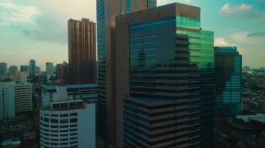 İnsansız hava aracı, sıcak altın saat ışığını yansıtan cam gökdelenleri yakalıyor ve çarpıcı bir şehir manzarası yaratıyor. Modern mimari arka plandaki şehir siluetiyle çelişiyor.