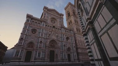 FLORENCE, ITALY - 15 Ağustos 2024: Meşhur Santa Maria del Fiore Katolik Kilisesi, gün batımının son saatlerinde gökyüzünün altında mermer cepheli. St. Mary 'nin eski Katedrali Akşam caddesinde büyülenmiş çiçek manzaralı
