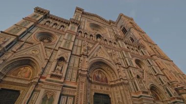 FLORENCE, ITALY - 15 Ağustos 2024: Eski Santa Maria del Fiore cephesi mavi gökyüzü altında azizlerin freskleri ve kemerleriyle. St. Mary 'nin ünlü Katedrali. Eski kasabada, alacakaranlıkta gotik bir çiçekle.