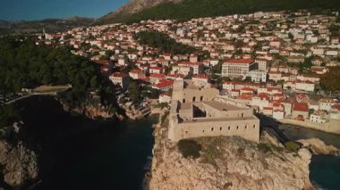 St. Lawrence kale kulesi dağın alt tarafındaki küçük bir kasabaya karşı hareket halinde. Dubrovnik 'teki parlak güneş ışığında uçurumun kenarındaki ortaçağ erişilmez kalesi Hırvatistan hava sahası