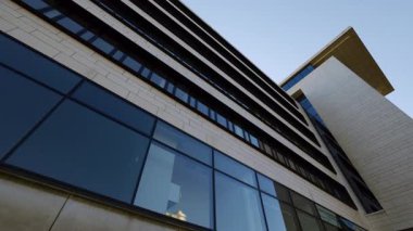 Şehir merkezinde ön cephede panoramik pencereleri olan modern ofis binası. Şehir sokaklarında iş ve ticaret için minimalist kentsel mimarlık projesi. Yer imi görünümü