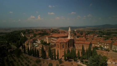 İtalya 'nın Toskana bölgesindeki Pienza kasabasının insansız hava aracı görüntüleri. Gündüz vakti ikonik kilise, selvi ağaçları ve manzaralı kırsal kesimlere ev sahipliği yapıyor.