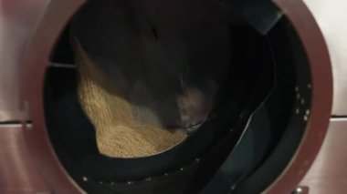 Metalik bir varilde ham taneleri döndüren bir besin işleme makinesinin içine yakından bakın. Otomatik tahıl işleme ve üretiminde kullanılan endüstriyel ekipmanlar.