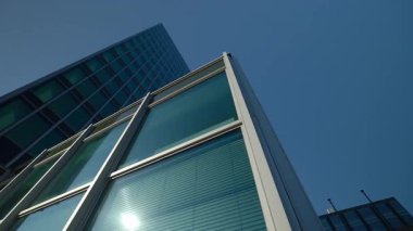 Panoramik pencereli cam ofis köşesi mavi gökyüzü alçak açılı çekimin altındaki güneş diskini yansıtıyor. İş merkezi şehir mimari projesi. Şehir merkezi yapısı gözlemleniyor