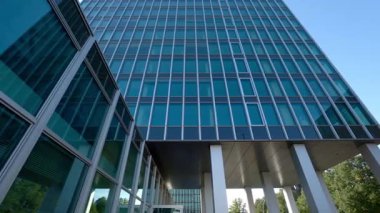 Şehir merkezindeki düşük açılı çekimde aynalı cam cepheli ofis binası. Şehir caddesindeki ofis merkezi çok katlı kule. Sanayi gayrimenkulleri