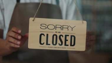 Kapalı kapılar ardında genç garsonlar, cam kafenin kapısına açılan tabelayı çevirdiler. Önlüklü fast food restoranı çalışanı davetiye tabağı gösteriyor. Yerel kahve dükkanı müşteri hizmetleri