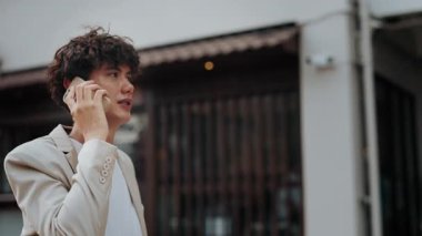 Şehirde cep telefonuyla konuşan neşeli, kendine güvenen bir adamın portresi. Akıllı ceketli genç serbest çalışan, sokakta cep telefonuyla konuşuyor. İş anlaşması