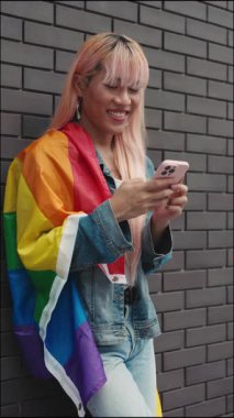 Dikey video. Olumlu Genç LGBT Adam Peruk Durma ve Telefon Kullanma, Mesaj. Akıllı Telefon Kullanarak Yakışıklı Adam Sohbetleri Sosyal ağlardaki fotoğraflara bakıyor. LGBT ve Teknoloji Konsepti
