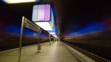 HAMBURG, GERMANY - 23 Eylül 2024: Yer altında parlayan renk küpleriyle Hafencity Üniversitesi metro istasyonu platformu. Modern şehirde seyahat eden yolcular için toplu taşıma hizmeti